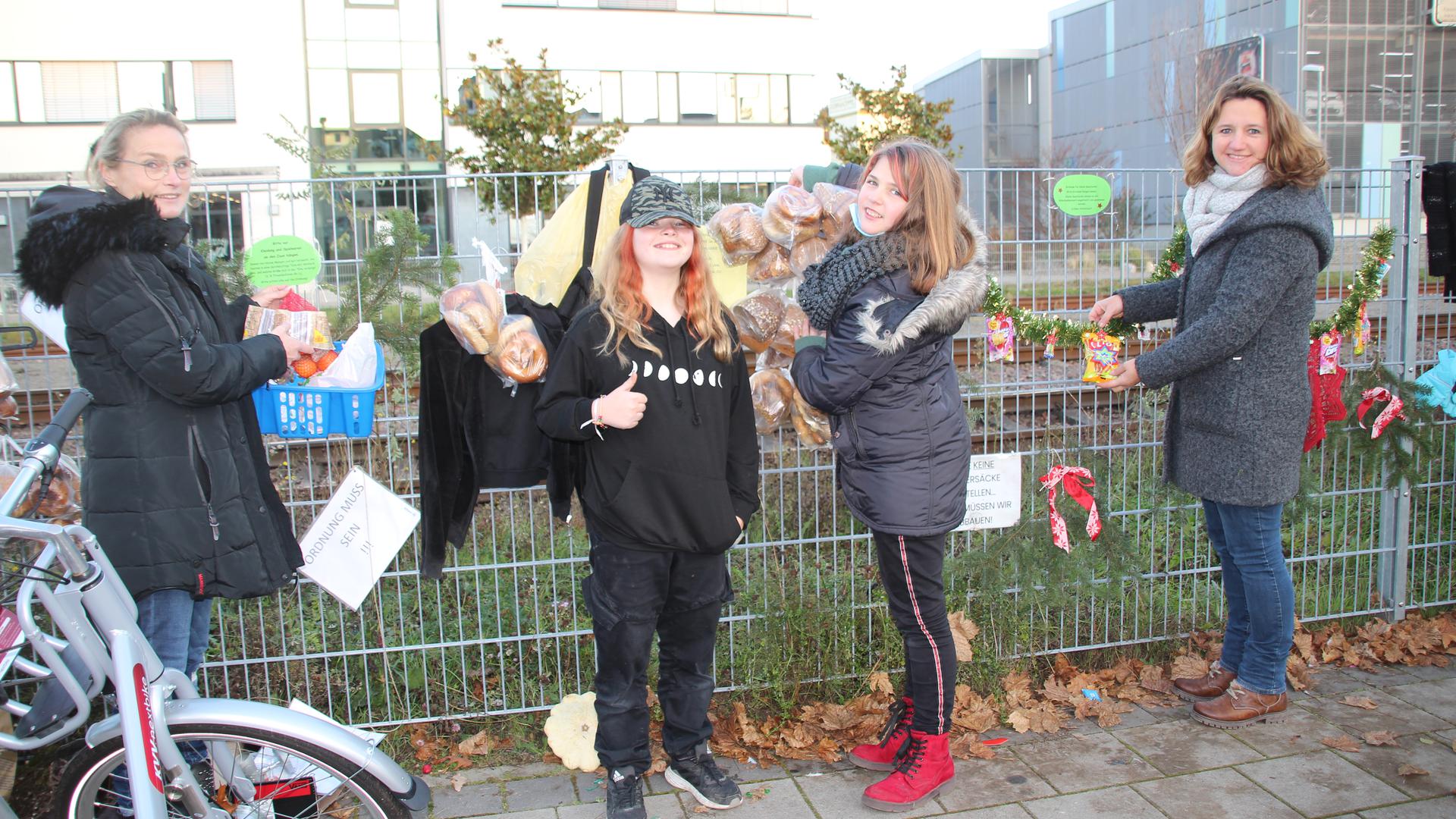 Andrea Harrer (links) und Alexandra Weber-Holfelder (rechts) bestücken den Gaggenauer Gabenzaun am Bahnhof mit Backwaren, Obst und Gemüse. Ihre Töchter helfen ihnen dabei.
