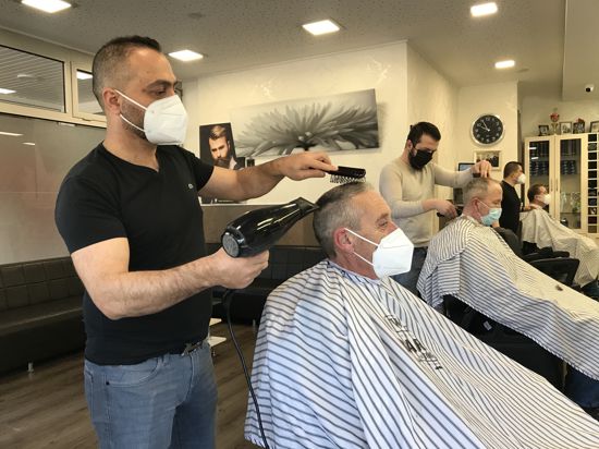 Ein Friseur schneidet einem Mann die Haare.
