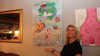 Ratsstübel-MItarbeiterin Erika Rubel mit einem von ihr gemalten Bild. Es hängt im Gastraum des Gaggenauer Ratsstübel gleich rechts. Das Bild zeigt Fische, einer Comic-Darstellung nicht unähnlich.