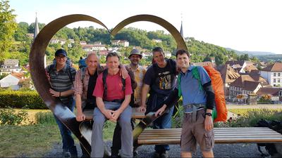 Sechs Wanderer an einem Metallherz mit Bank und Tisch in Weingarten