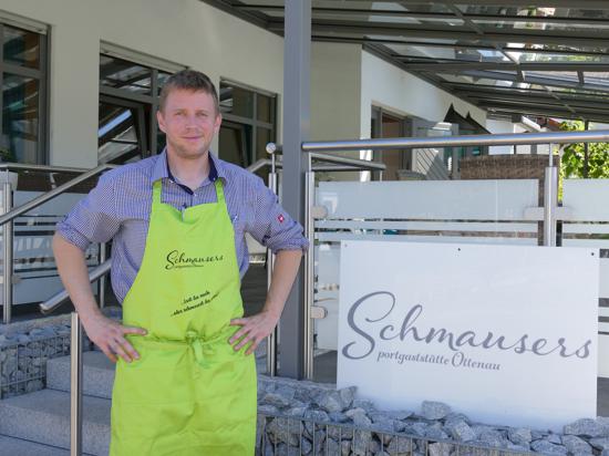 Gastronom Mattias Schmauser hat eine hellgrüne Schürze umgebunden und steht vor der Terrasse von Schmausers Sportgaststätte in Ottenau.
