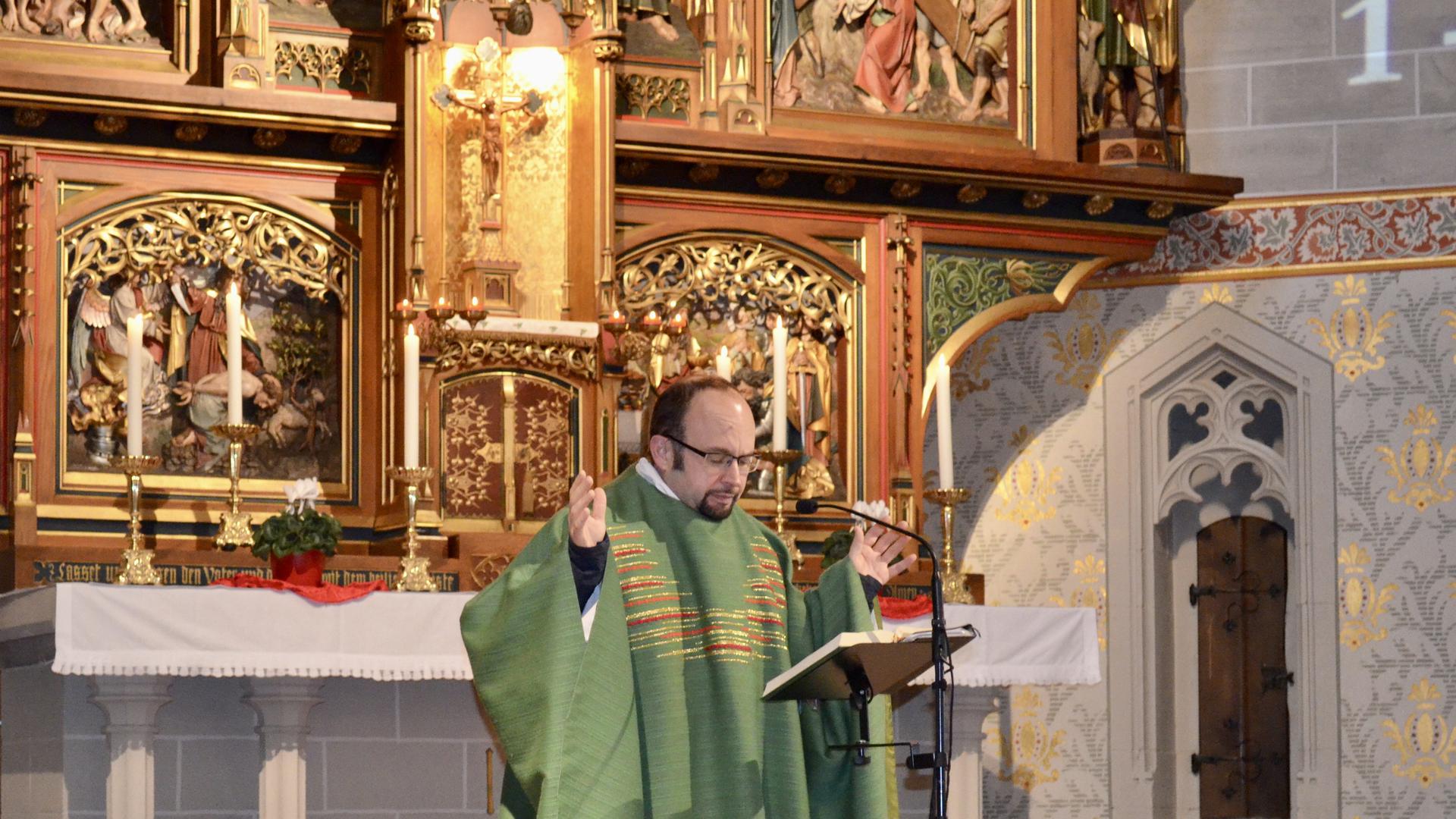 ein Pfarrer im Ornat steht vor einem goldenen Altar in einer Kirche in Gaggenau und predigt