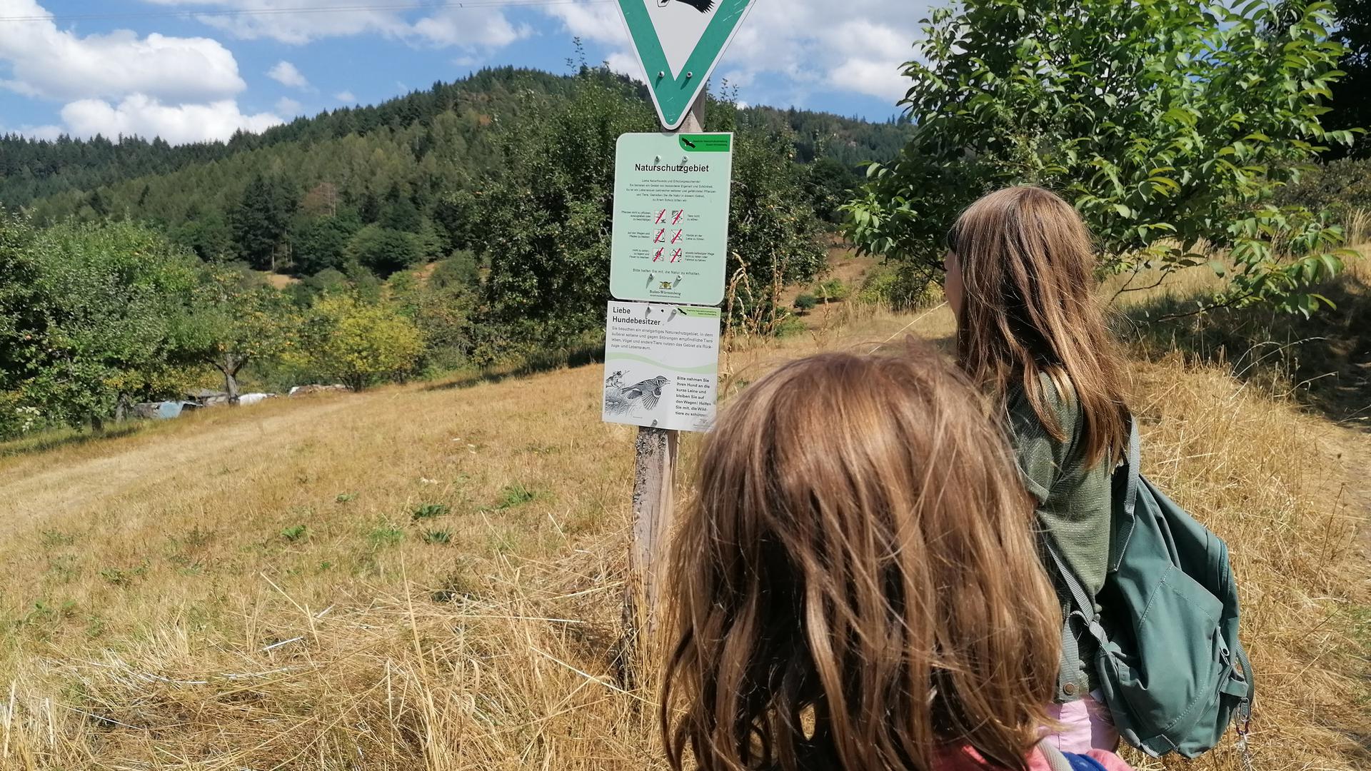 Kinder schauen auf ein Schild im Naturschutzgebiet