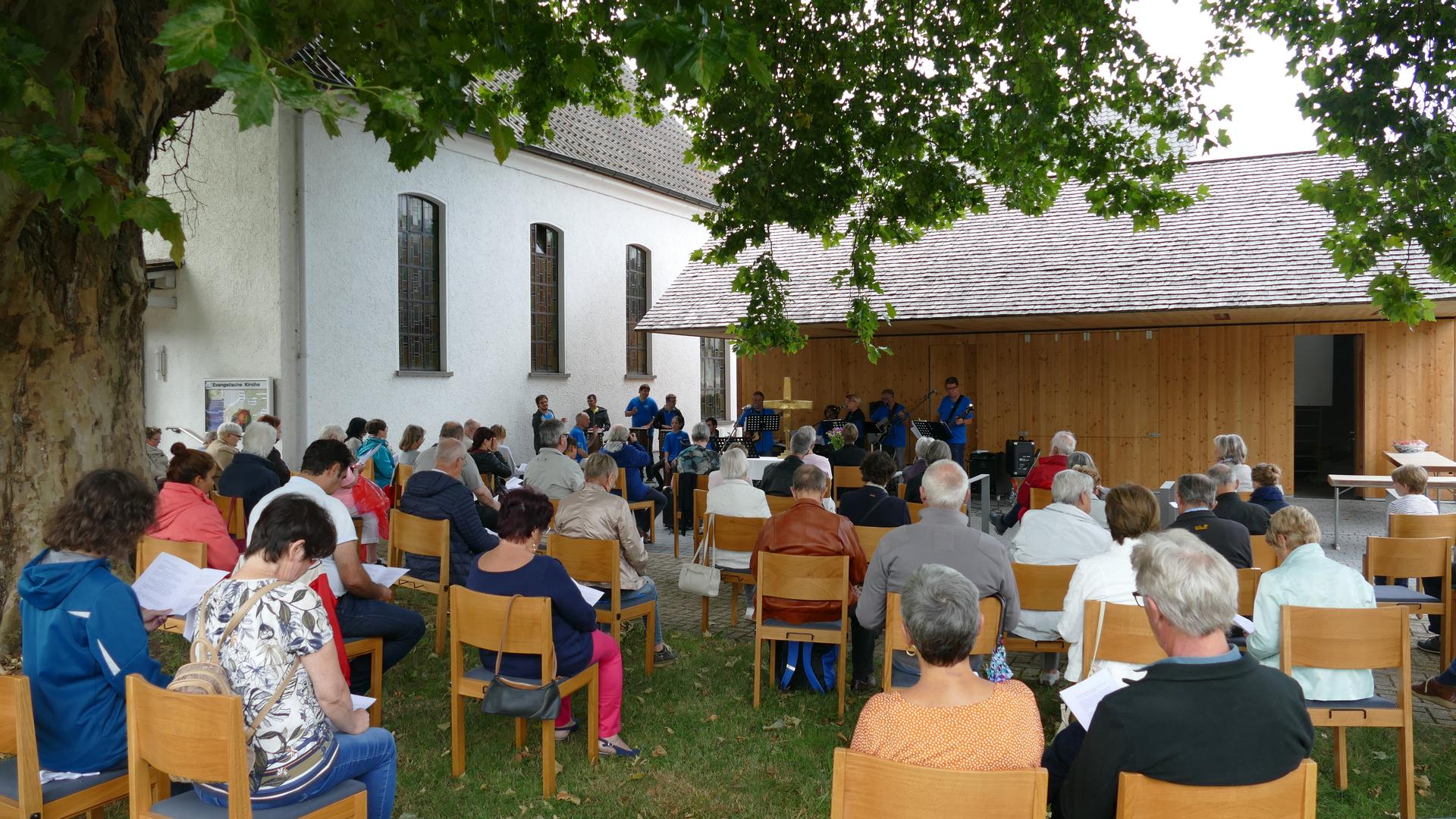 Radfahrerkirche Gaggenau Hörden. Open Air Gottesdienst September 2020. Mehrere Menschen sitzen auf Stühlen auf einer Wiese unter einem Baum.