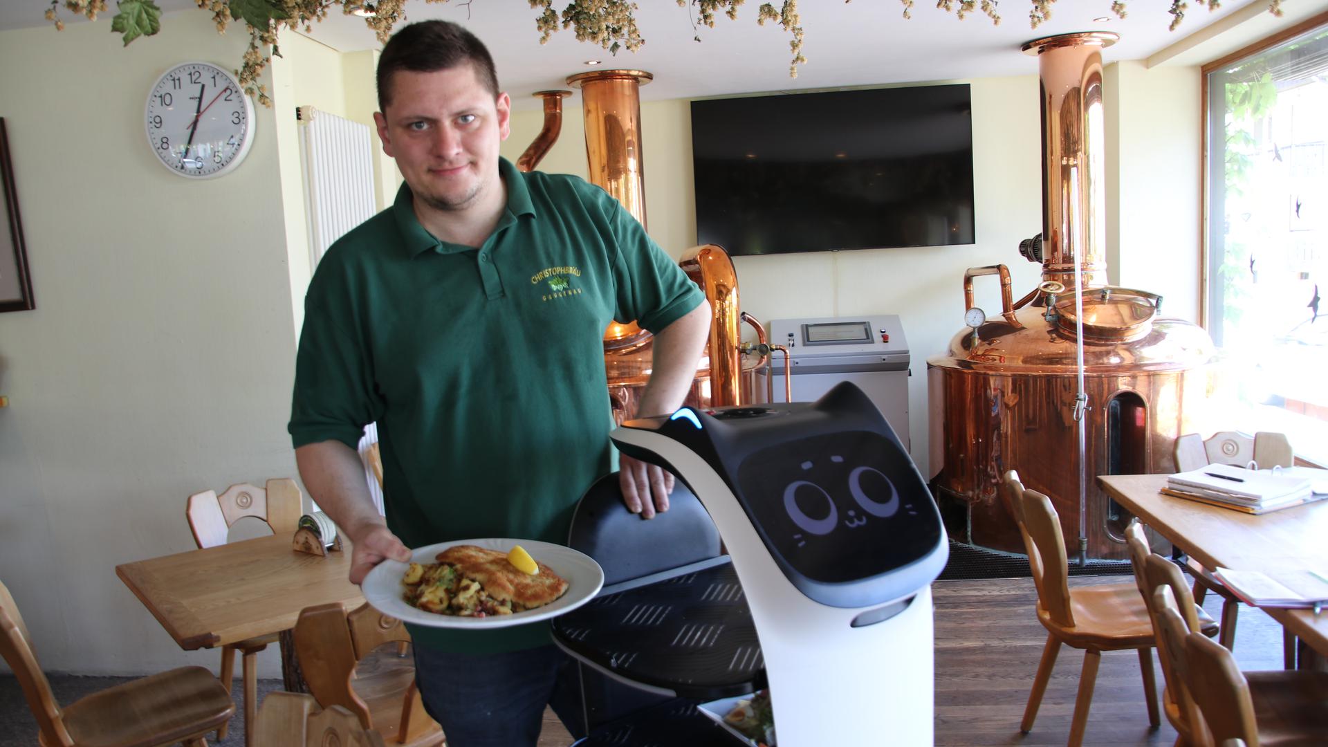 Patrick Raum serviert im Christophbräu Gaggenau zusammen mit Roboter Bella das Mittagessen.
