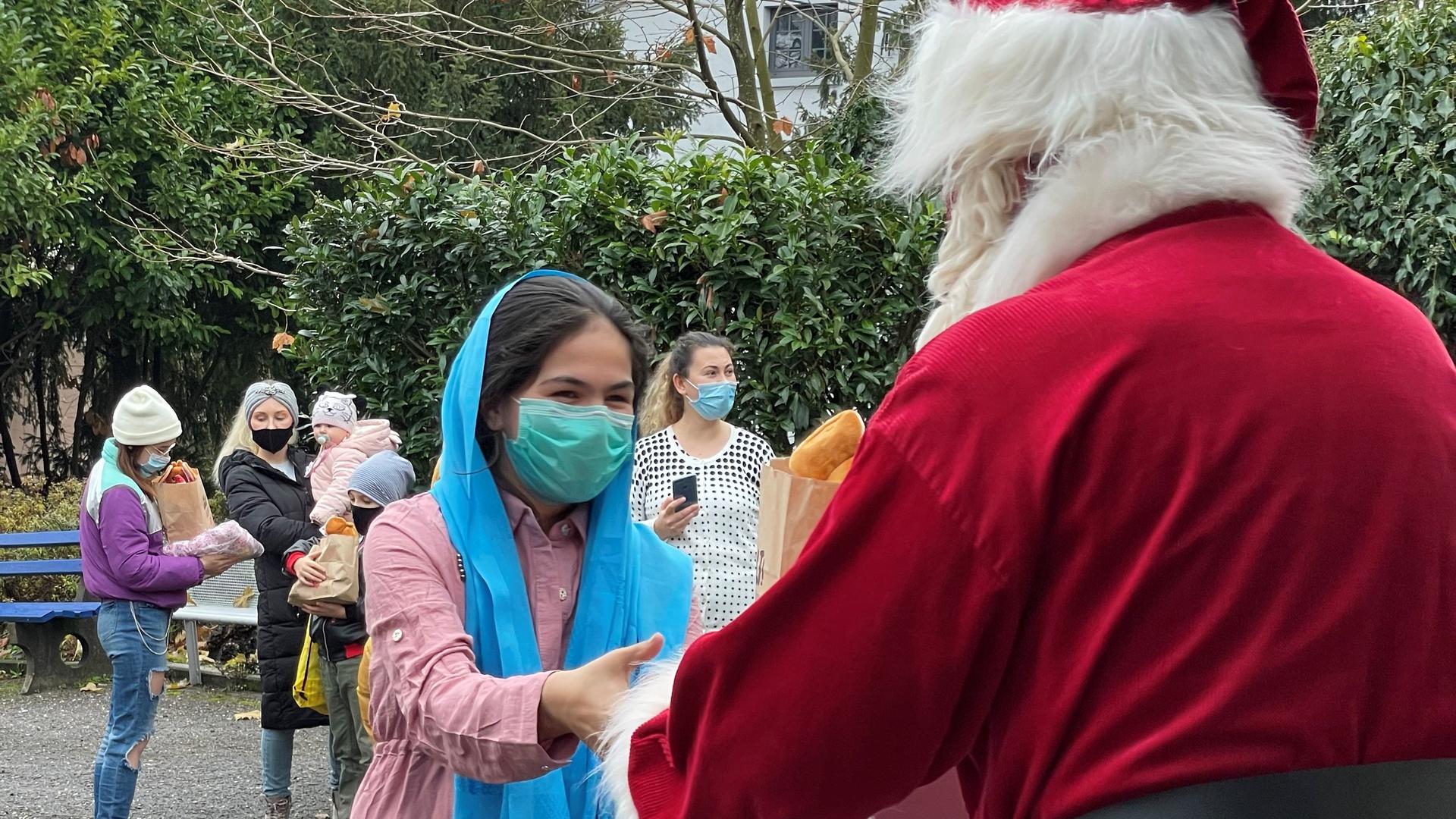 Ein Weihnachtsmann übergibt einem Mädchen Geschenke.