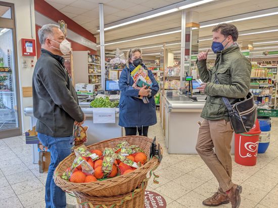 Ein Mann steht in einem Supermarkt und unterhält sich mit einem Ehepaar.