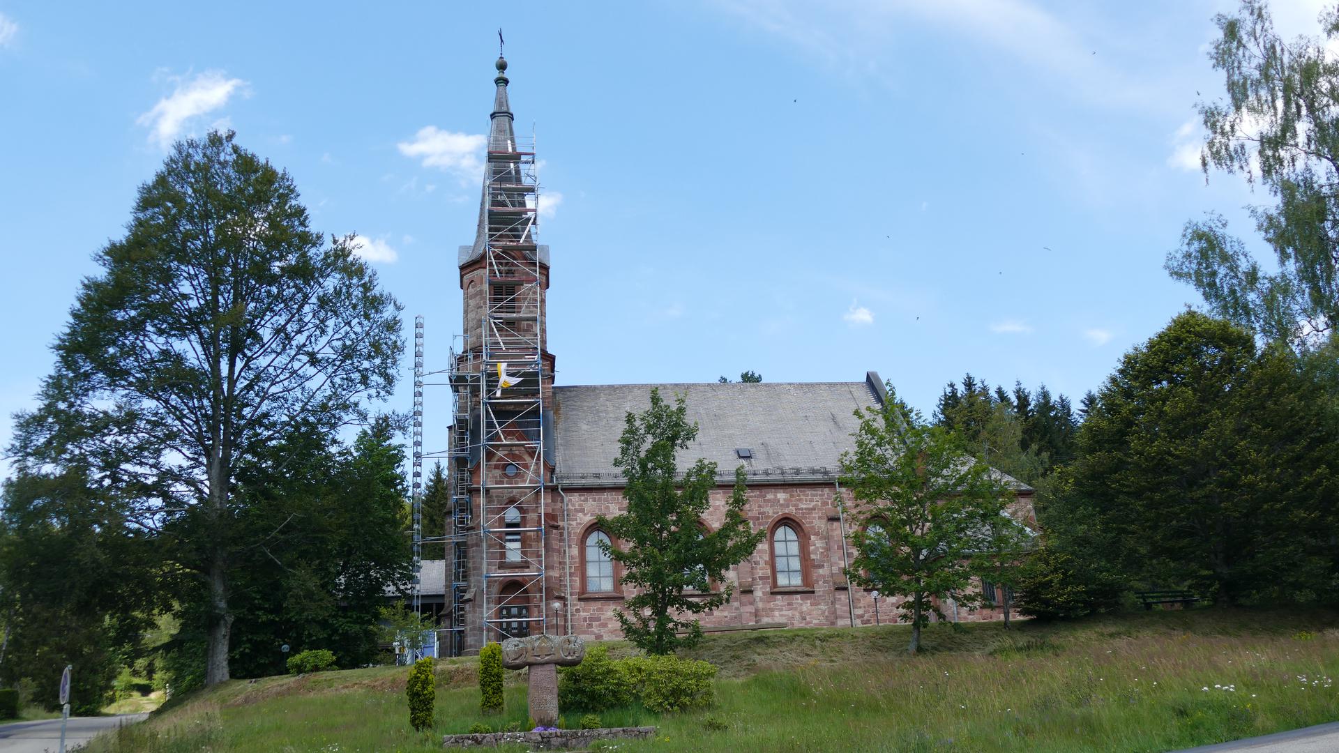 Pfarrkirche Herrenwies, Seitenansicht mit Baum, Baugerüst und Gedenkstein