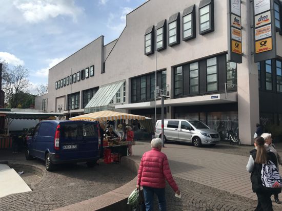 Marktstand und Lieferfahrzeuge vor einem Kaufhaus.