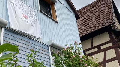„Schweren Herzens nehmen wir Abschied von unserem freien Michelbach“ steht auf einem Banner, das an einer blauen Hausfassade hängt.