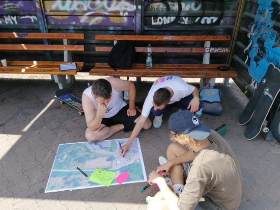 Junge Erwachsene blicken auf einen Stadtplan und zeichnen ein, wo und wie sie sich mehr Aufenthaltsqualität vorstellen können.