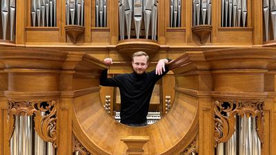 Ein Mann steht vor einer großen Orgel.