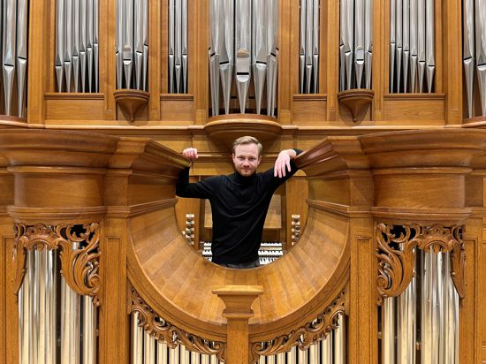 Ein Mann steht vor einer großen Orgel.