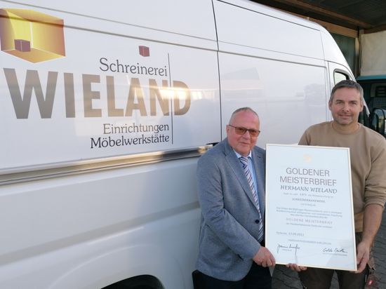 Hermann und Marco Wieland von der Schreinerei Wieland mit Goldenem Meisterbrief vor einem Firmenfahrzeug.