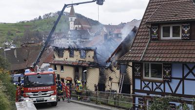 Einsatzkräfte löschen ein Feuer in Gernsbach, bei dem drei Menschen gestorben sind. Nach dem Brand haben die Ermittler eine „verdächtige Person“ im Blick.
