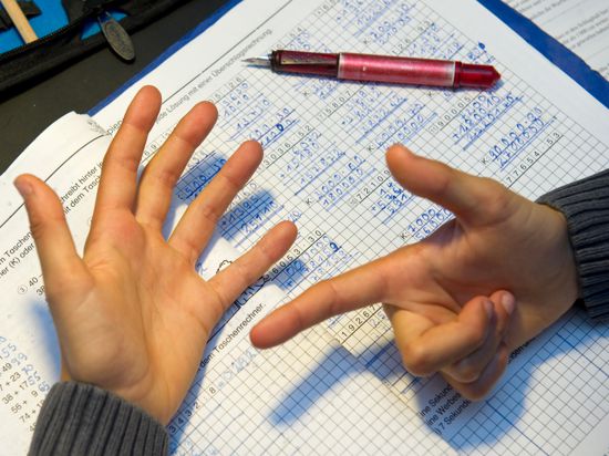 Ein achtjähriger Junge nimmt bei den Hausaufgaben im Fach Mathematik seine Finger zu Hilfe.