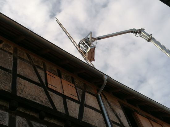 Ein Kranwagen hievt die Holzleiter über die Zehntscheuern, um sie übers Dach zu installieren.