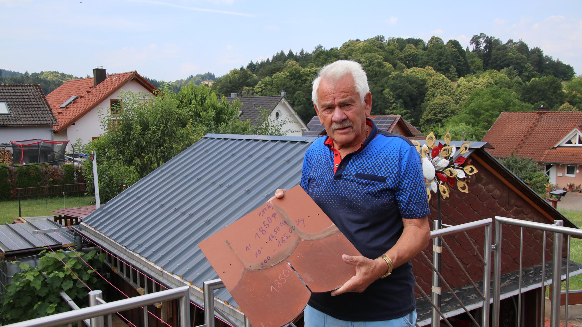 Roland Schweikart zeigt auf dem Balkon einen seiner Biberschwänze, die 40 auf 40 Zentimeter groß sind. Im Hintergrund ist das neue Dach seines Wintergartens zu sehen.