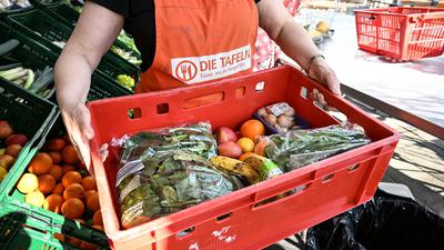 Eine Mitarbeiterin eines Tafel-Ladens trägt eine Kiste voll mit Obst und Gemüse. Für Menschen in Not sind die Tafeln in Baden-Württemberg wichtige Anlaufstellen.