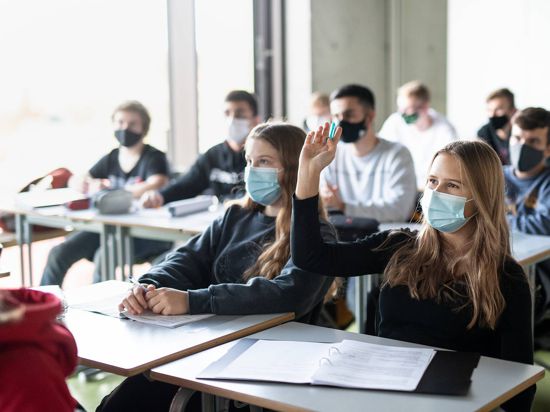Schüler büffeln an einem Gymnasium mit Maske.
