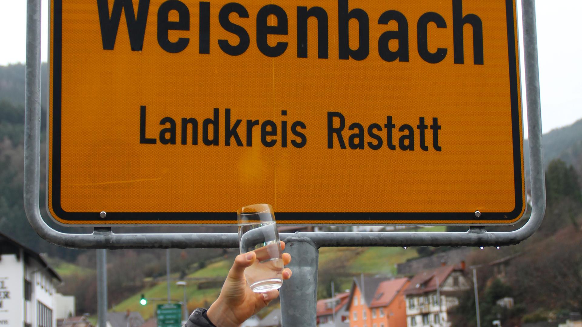Ein Glas Wasser vor dem Ortsschild von Weisenbach