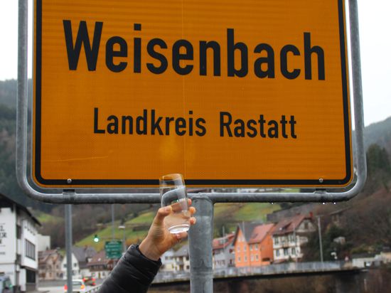 Ein Glas Wasser vor dem Ortsschild von Weisenbach
