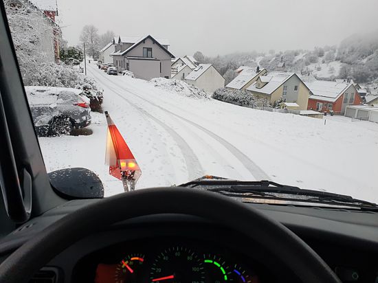Blick aus einem Räumfahrzeug auf ein verschneites Dorf.