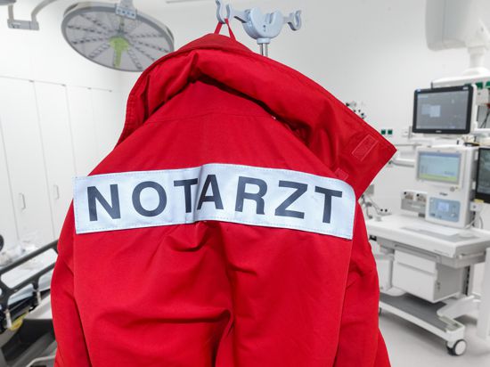 Eine rote Jacke mit der Aufschrift "Notarzt" auf dem Rücken hängt im Schockraum.