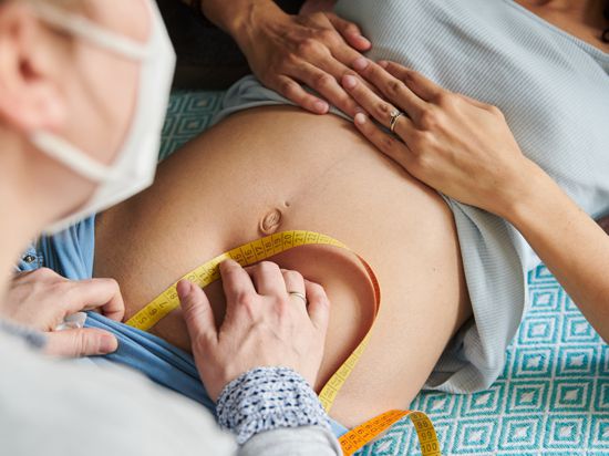 Mit einem Maßband misst eine Hebamme in ihrer Praxis den Symphysen-Fundus-Abstand bei einer schwangeren Frau. Symphysen-Fundus-Abstand bezeichnet die Länge zwischen Schambein und dem höchsten Punkt der Gebärmutter. (zu dpa «Studie: Corona geht mit etwas erhöhtem Risiko von Totgeburten einher») +++ dpa-Bildfunk +++