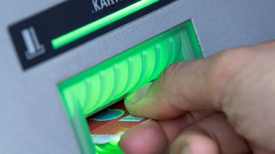 ILLUSTRATION - Eine Bankkundin steckt ihre Girokarte in einen Geldautomaten. (zu dpa "Entwicklung der Kontogebühren") +++ dpa-Bildfunk +++