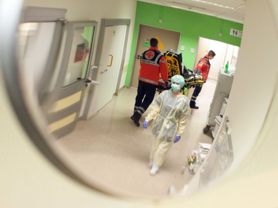 Eine Krankenschwester mit Mundschutz geht durch eine Notaufnahme.