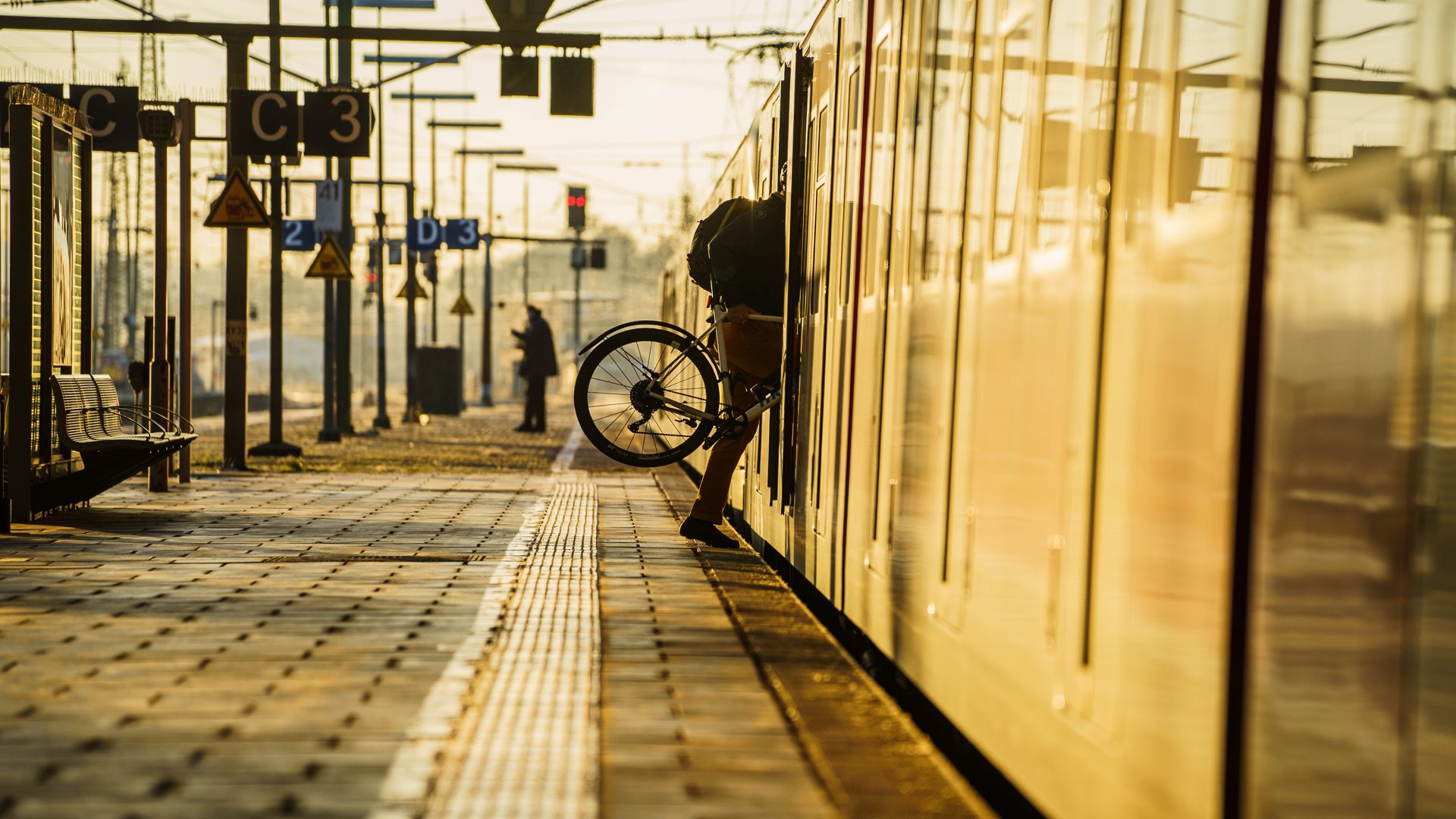 Ein Bahnreisender hebt sein Fahrrad in eine Bahn.