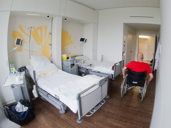 Ein Patient fährt  mit einem Rollstuhl durch ein Zimmer.
