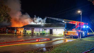Drehleiter der Feuerwehr löscht in morgendunkler Zeit das brennende Sportheim in Kehl-Kork
