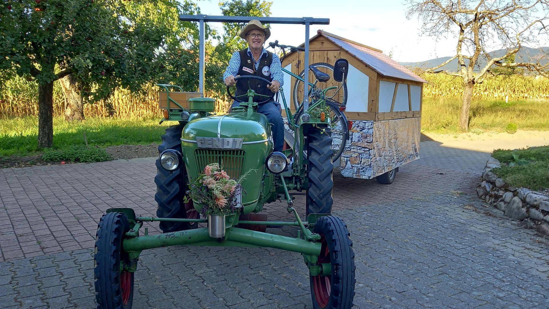 Mann auf Traktor mit Wohnwagen-Anhänger