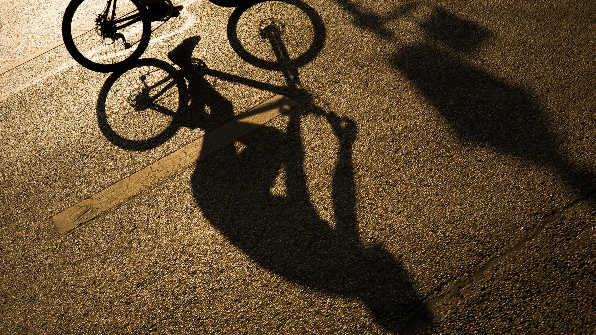 Der Schatten eines Radfahrers zeichnet sich in Licht der Abendsonne auf dem Asphalt einer Strasse in der Innenstadt ab. (zu dpa «Umfrage: Viele Bürger wollen auch nach Corona mehr mit dem Rad fahren»)