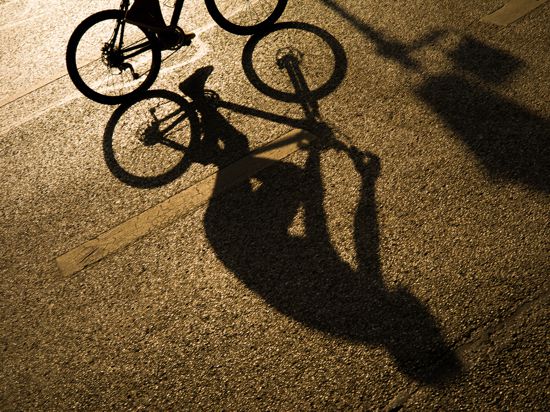 Der Schatten eines Radfahrers zeichnet sich in Licht der Abendsonne auf dem Asphalt einer Strasse in der Innenstadt ab. (zu dpa «Umfrage: Viele Bürger wollen auch nach Corona mehr mit dem Rad fahren»)