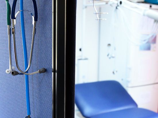 Stethoskope hängen im Behandlungszimmer einer Hausarztpraxis über einer Trennwand. 