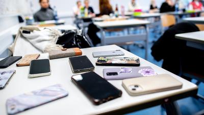 Zahlreiche Smartphones der Schülerinnen und Schüler liegen vor Beginn der schriftlichen Abiturprüfungen im Fach Geschichte auf einem Tisch.