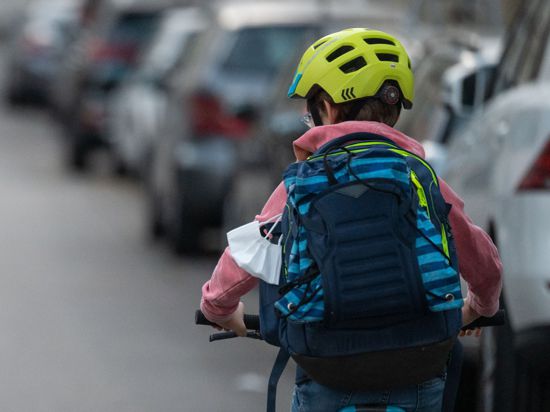 Ein Schulkind fährt mit seinem Fahrrad eine Straße entlang. 