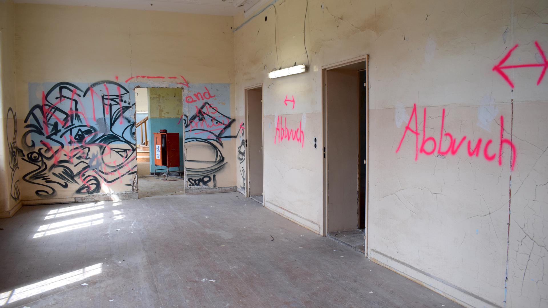 Ein Flur mit Graffiti-Gemälde und dem aufgesprühten Wort „Abbruch“ an den Wänden.