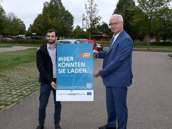 Acherns Bürgermeister Dietmar Stiefel und Sven Hübschen vom ACE werben am Park+Ride-Platz am Acherner Bahnhof mit einem Plakat für die Verkehrswende.