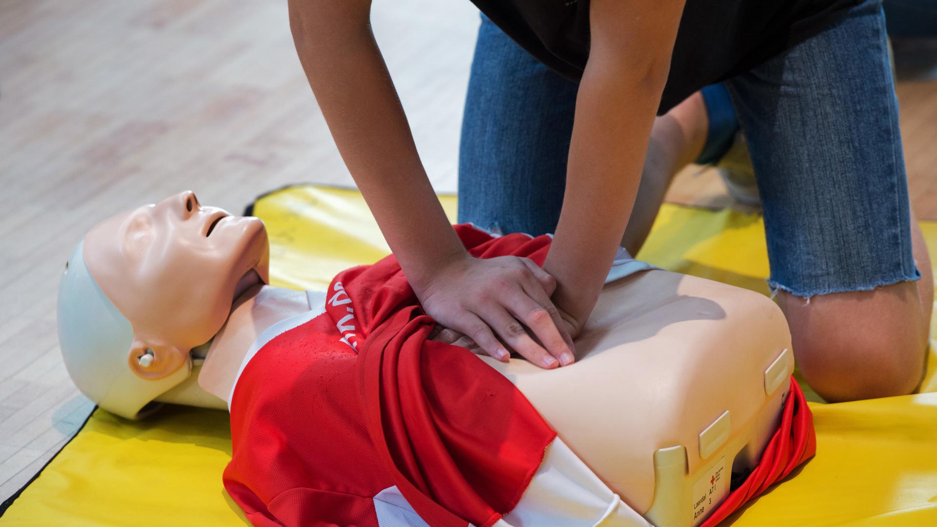 Erste Hilfe, Ersthelfer, Erste-Hilfe-Kurs mit einem Dummy, bei dem Herzdruckmassage durchgeführt wird. 