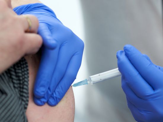 In einem Impfzentrum wird ein Mann gegen Corona geimpft