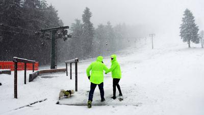Zwei Männer arbeiten im ersten Schneefall am Skilift am Ruhestein im Schwarzwald.