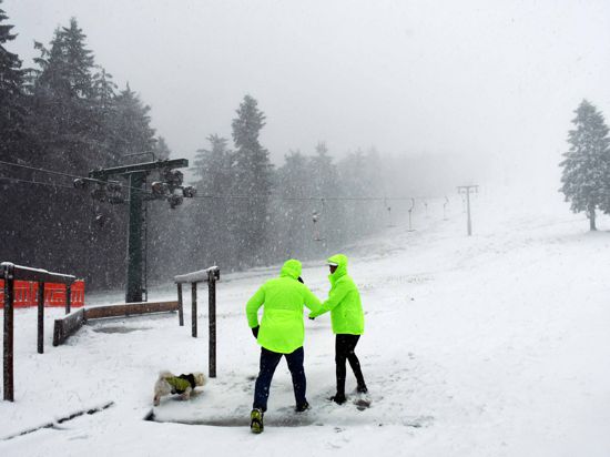 Zwei Männer arbeiten im ersten Schneefall am Skilift am Ruhestein im Schwarzwald.