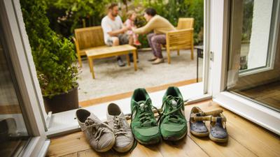 Blick auf eine Terasse mit Familie und Schuhen iin verschiedenen Größen.