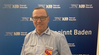 Klaus Rauber steht vor der blauen Werbefläche des ABB.