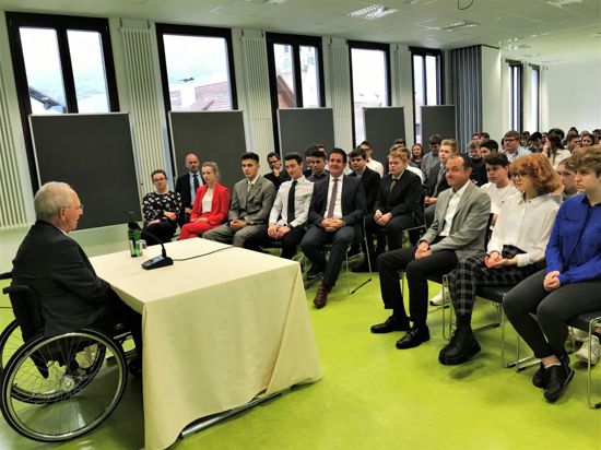 Wolfgang Schäuble sitzt vor einer Gruppe Schülern