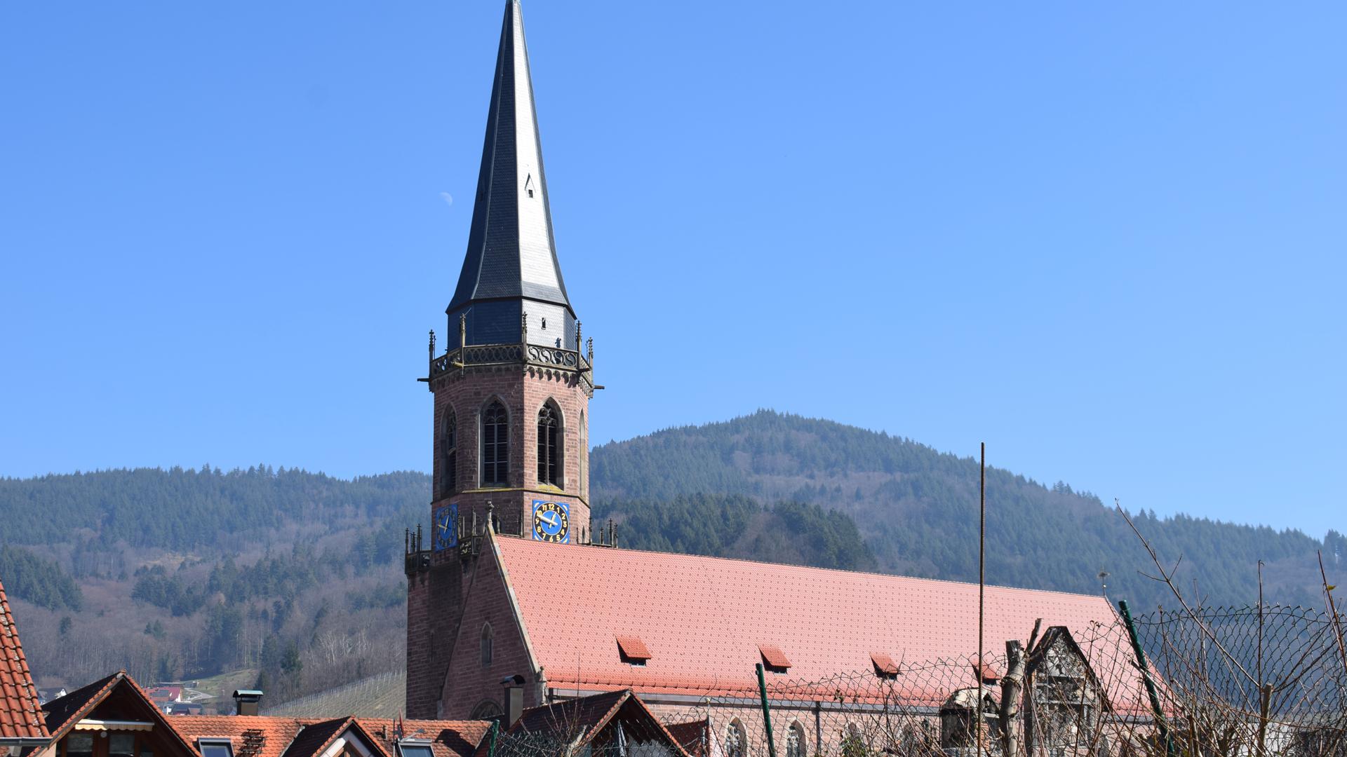 Pfarrkirche St. Nikolaus in Kappelrodeck vor Bergen und blauem Himmel.
